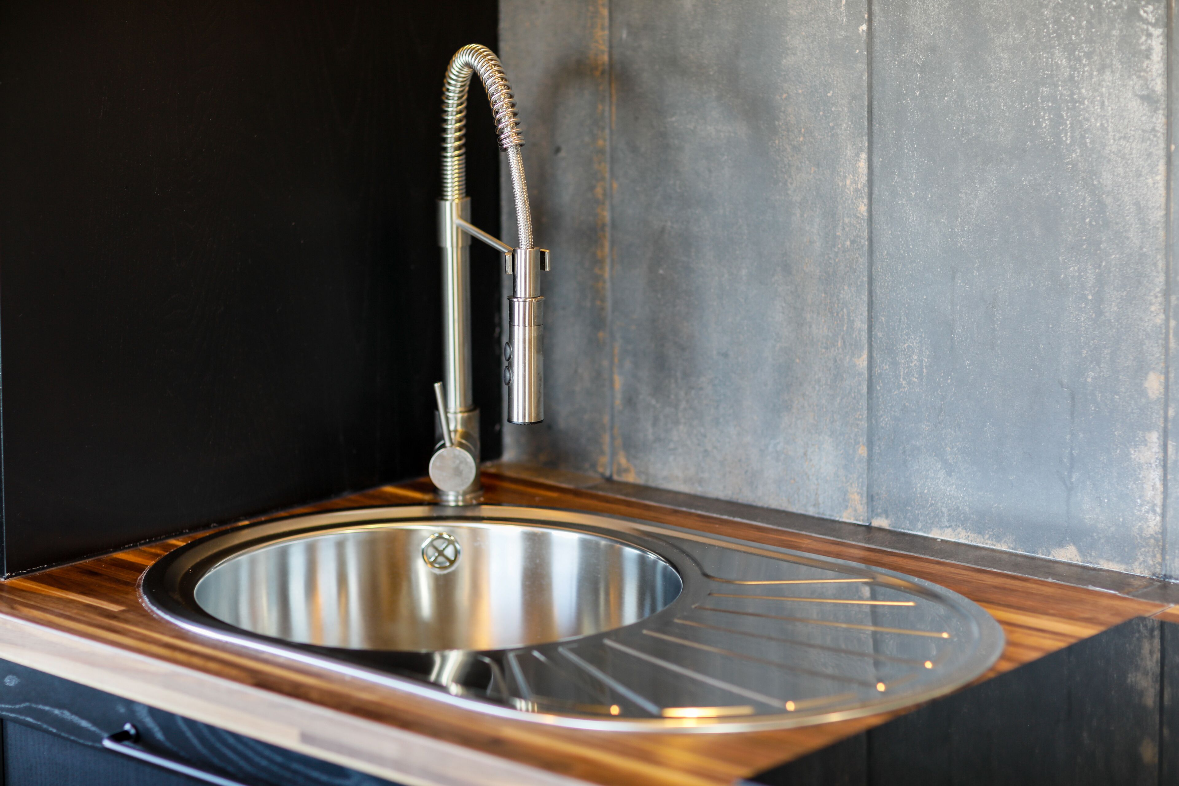 A modern kitchen sink with a stainless steel basin and a flexible faucet.