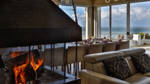 Una sala de estar moderna con chimenea, un sofá y vistas al océano.