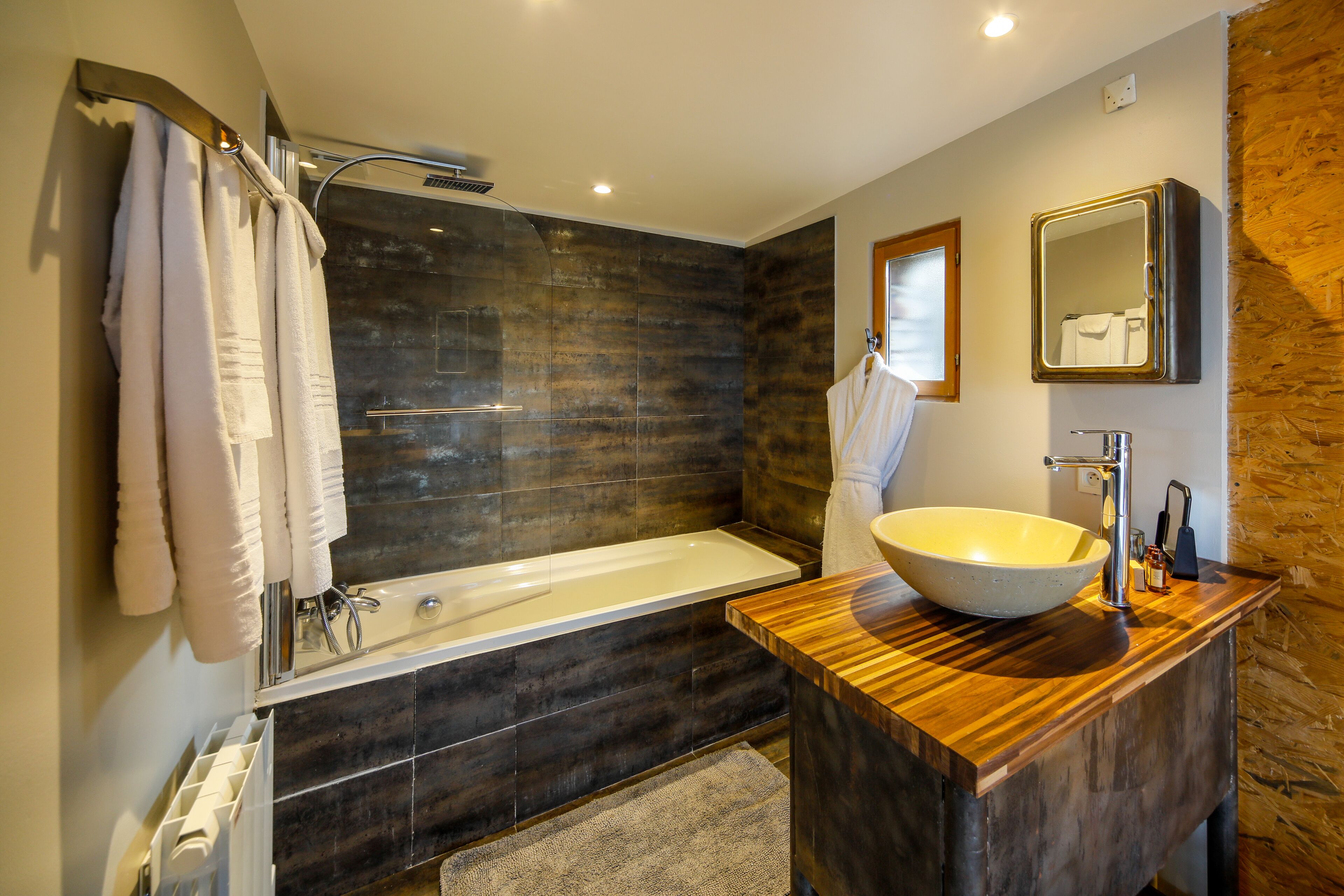 Ein modernes Badezimmer mit einer großen Badewanne, einem Holzbadezimmermöbel und einem großen Spiegel.