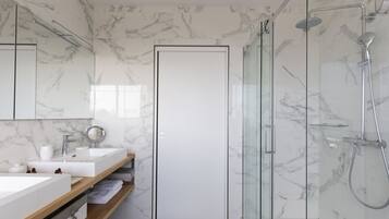 Une salle de bain moderne avec des murs en marbre, une douche en verre et une porte blanche.