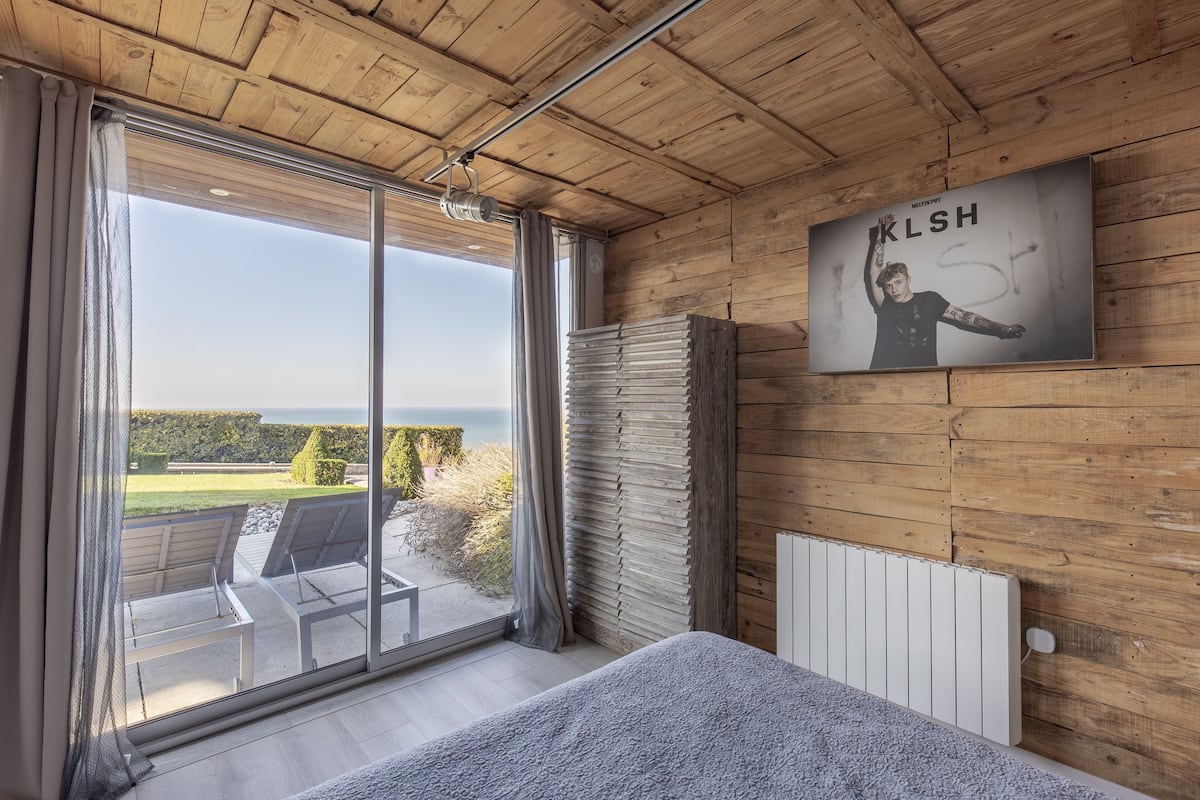 A room with a large window, wooden ceiling, and a poster on the wall.