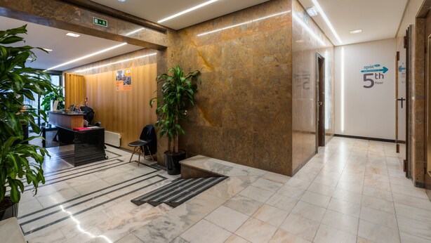 A modern lobby with a reception desk, potted plants, and a sign indicating the 5th floor. - Hotel Spot Family Suites (Porto)