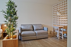 Ein modernes Wohnzimmer mit einer Couch, einem kleinen Tisch und einer Wanddekoration.