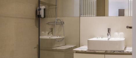 Un baño moderno con ducha de vidrio, un lavabo blanco con encimera de mármol y un espejo sobre el lavabo.