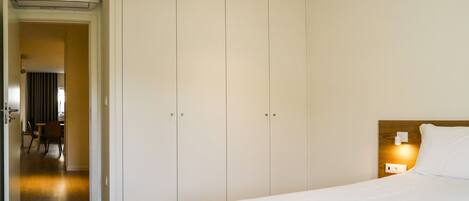 Une chambre d’hôtel avec un lit, une armoire, un bureau et une chaise.