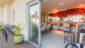 A modern apartment with a dining area, kitchen, and a balcony with potted plants. - Hotel Spot Family Suites (Porto)