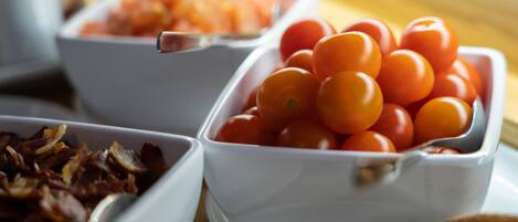 Un bufé de desayuno con diversos alimentos, incluyendo tomates, tocino y otros platos.