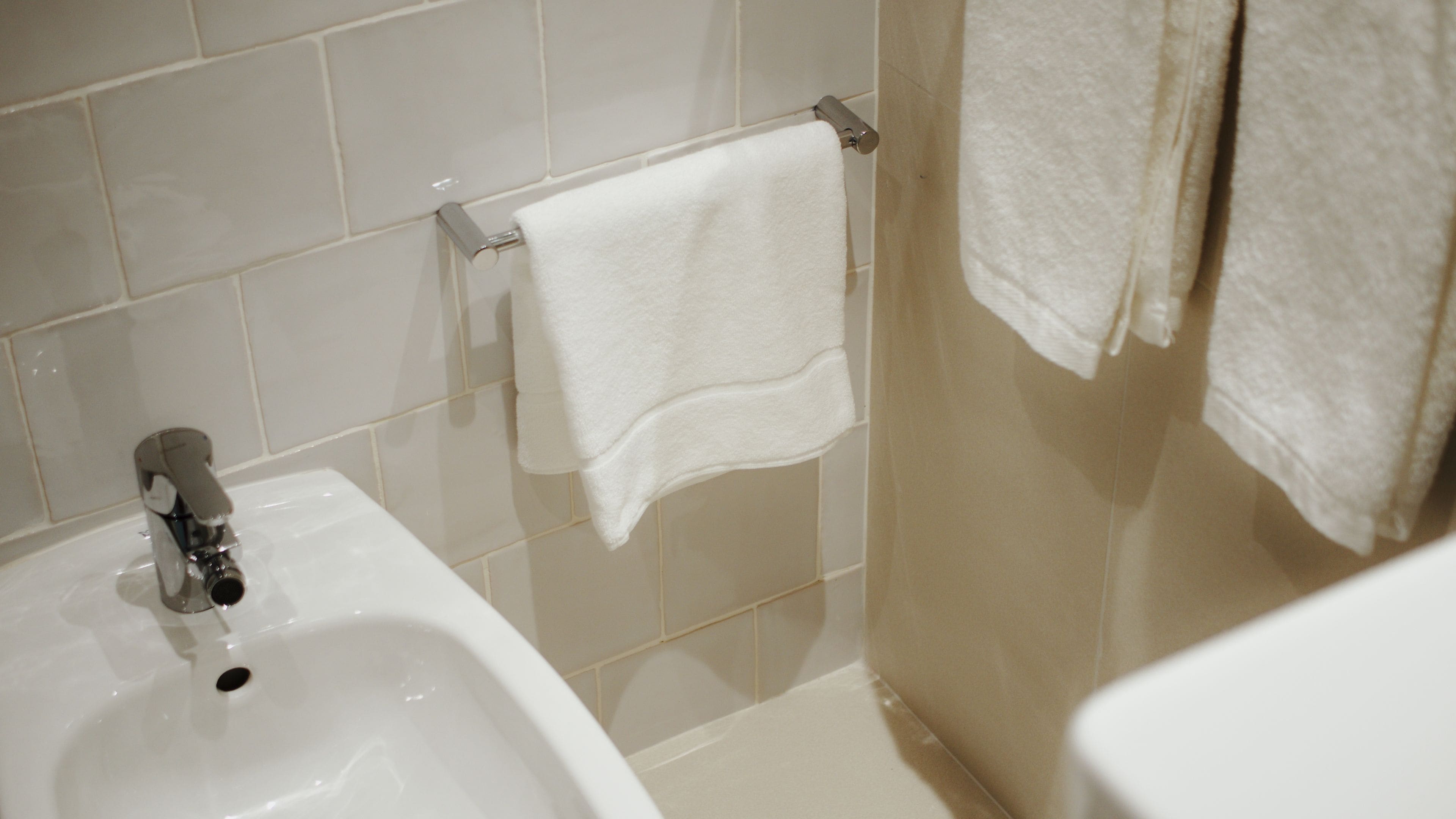 A bathroom with a white sink, a towel rack with a white towel, and a toilet.