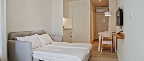 A modern bedroom with a bed, a sofa, a desk, and a chair.