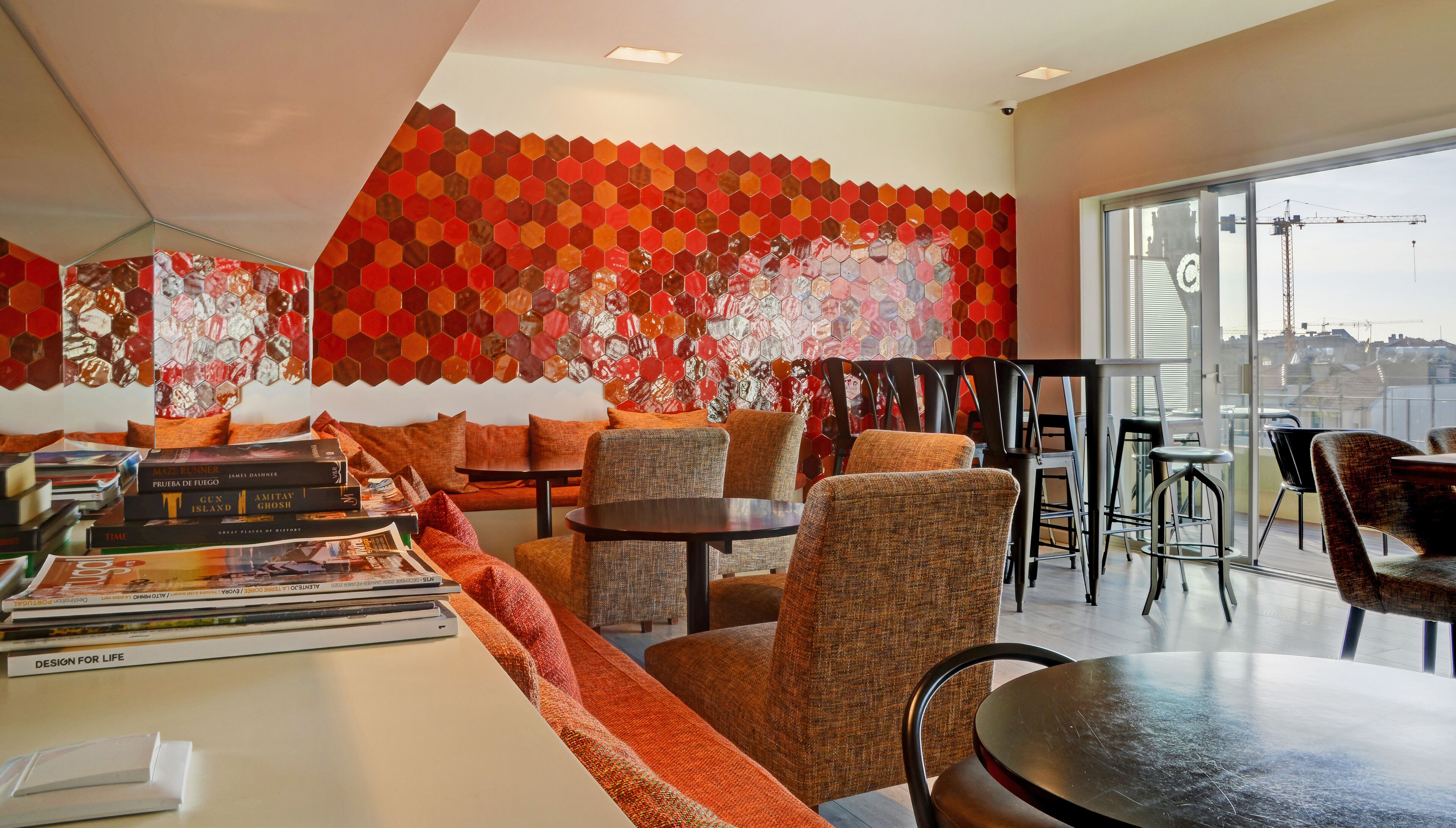 A modern lounge area with hexagonal patterned walls, comfortable seating, and a view of the cityscape through large windows.