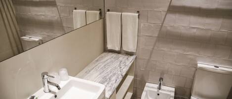 Une salle de bain équipée d’un lavabo, d’un miroir, d’un porte-serviettes et de toilettes.