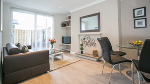 Un salon moderne avec un canapé, une table basse en verre, un téléviseur et une cheminée.