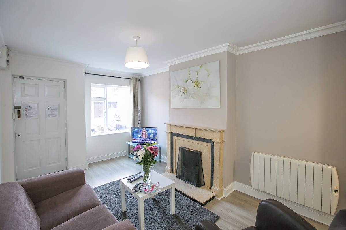 Ein Wohnzimmer mit Kamin, Fernseher und einer Couch.