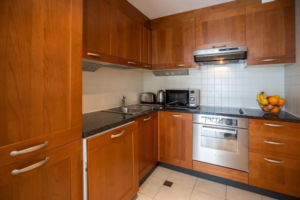 Eine Küche mit Holzausstattung, einer Mikrowelle, einem Toaster und einer Obstschale.