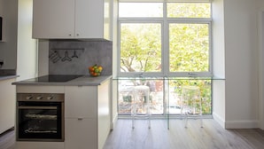 Une cuisine moderne dotée d’un four encastré, d’un banc-fenêtre en verre et offrant une vue sur l’extérieur.