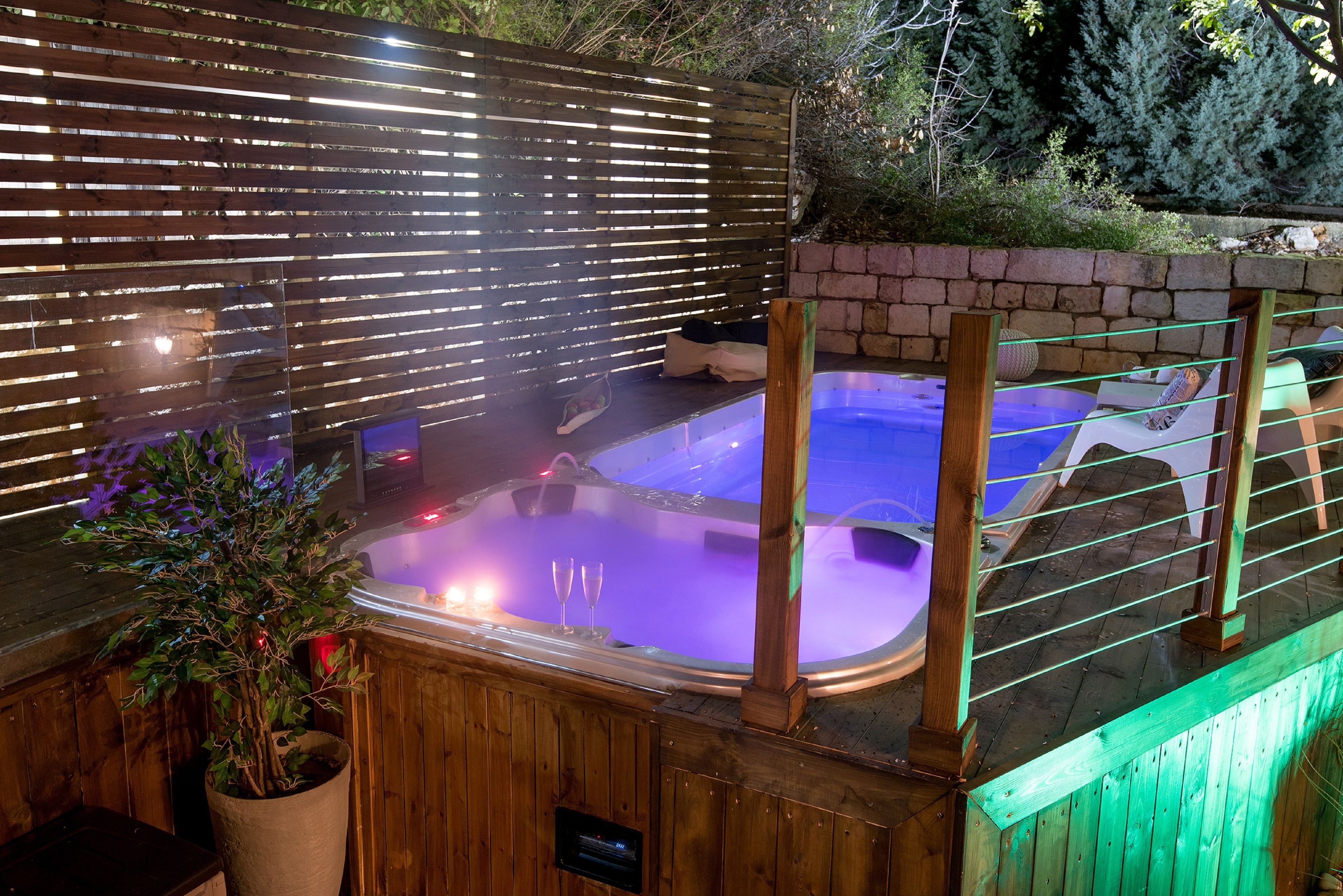 Un jacuzzi con una terraza de madera y una cerca de madera al fondo.