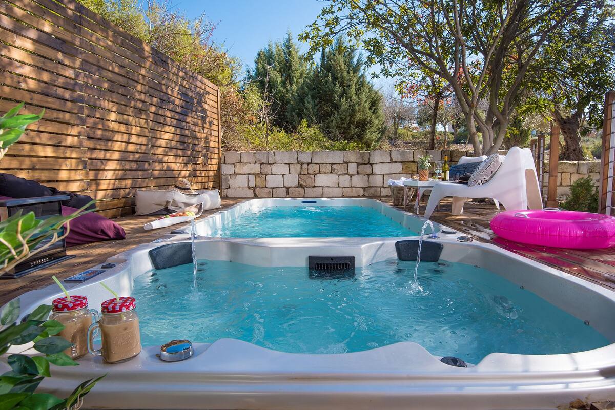 A backyard with two hot tubs, a stone wall, and a wooden fence.
