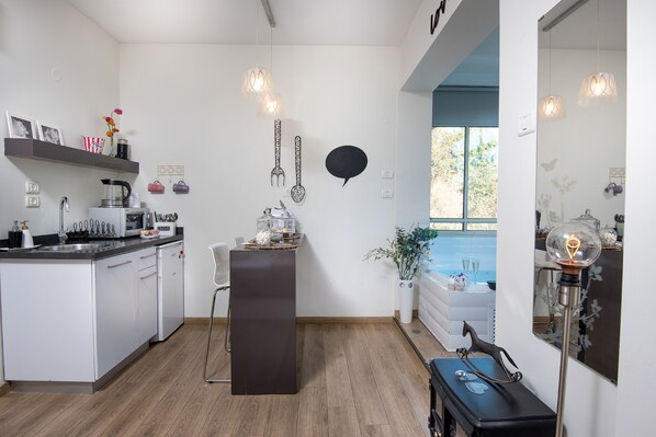 A modern kitchen with white cabinets, a central island, and pendant lighting. - Osnata Boutique Suites (Kfar Vradim)