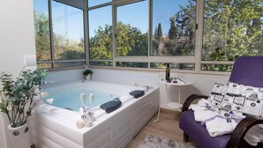 Ein Wellnessraum mit großem Fenster, Whirlpool und violettem Sessel.