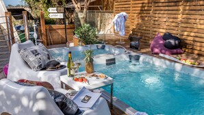 Ein Poolbereich mit Liegestühlen, einem Tisch mit Speisen und Getränken sowie einer Whirlwanne.