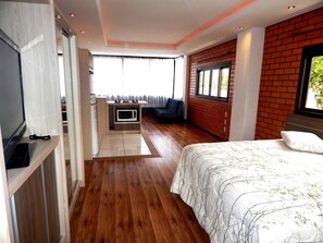 Une chambre avec un lit, un téléviseur encastré, un four à micro-ondes et un balcon avec vue.