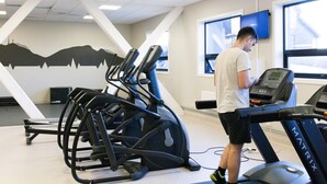 A gym with treadmills, a stationary bike, and a wall with a mountain silhouette. - Oslo Hostel Rønningen (Oslo)