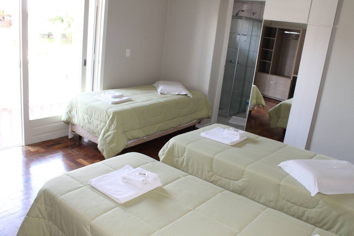A hotel room with two beds, a walk-in closet, and a bathroom with a glass shower.