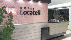 Una recepción de hotel con diseño moderno, que muestra un logotipo y el nombre 'HOTEL Locatelli'.