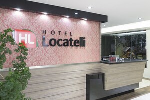 Uma receção de hotel com design moderno, apresentando um logotipo e o nome 'HOTEL Locatelli'.