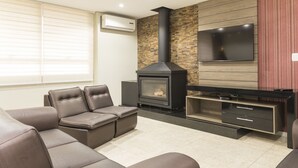 Una sala de estar moderna con chimenea, sofás de cuero, un televisor de pantalla plana y una pared de acento de madera.