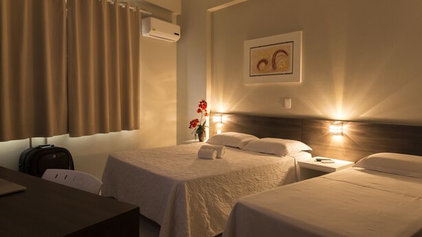 Habitación de hotel con dos camas, un escritorio, una silla y aire acondicionado de pared.