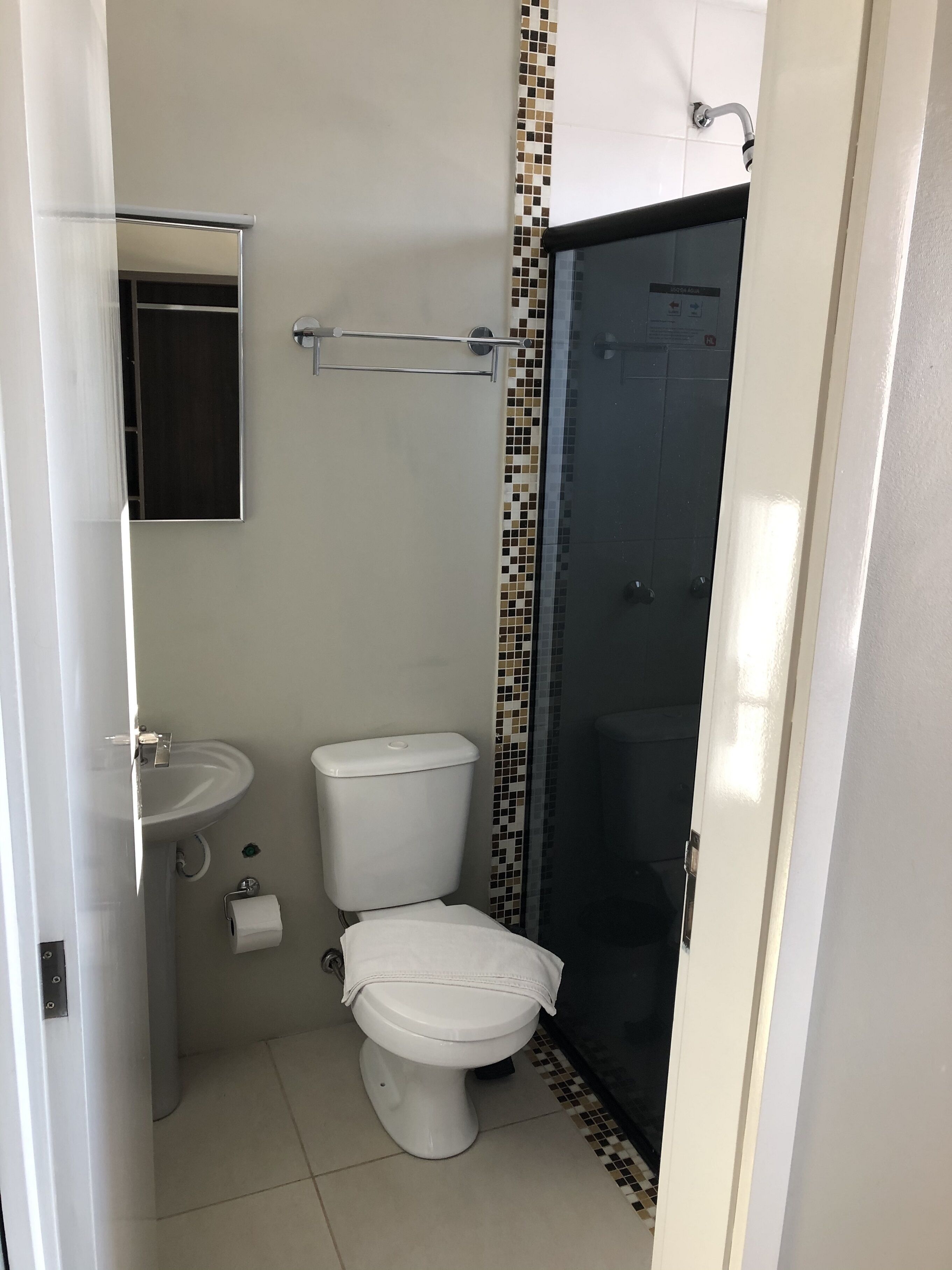 A compact bathroom with a toilet, sink, and shower.
