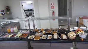 Un bufé con diversas opciones de comida y una cocina al fondo.