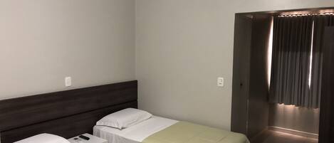 Habitación de hotel con dos camas individuales, un escritorio pequeño y una silla.