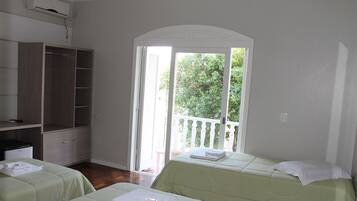 Una habitación con dos camas, un armario y un ventanal corredero que da a un espacio exterior.