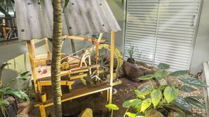 Una estructura de madera con techo de lámina corrugada, una rueda de bicicleta y una pequeña figura de madera.