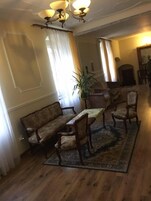 Un salón tradicional con sofá, sillas, mesa y candelabro.