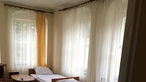 A room with two single beds, a small table, and a chair. - Palac Lasow (Piensk)