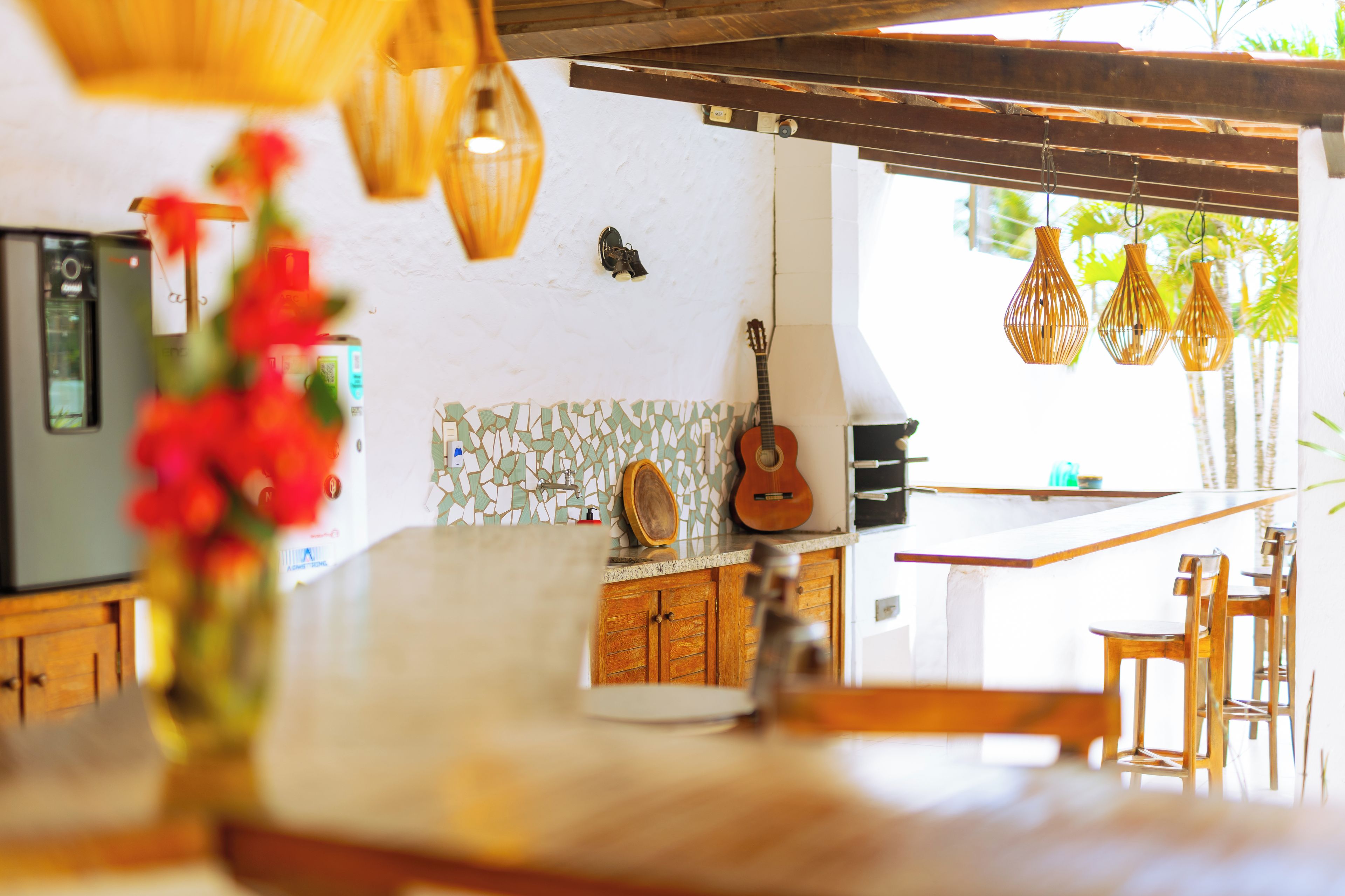 Una cocina con encimera blanca, armarios de madera, una guitarra y lámparas colgantes.
