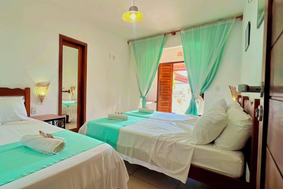 A hotel room with two beds, a wooden headboard, a nightstand, and a mirror.