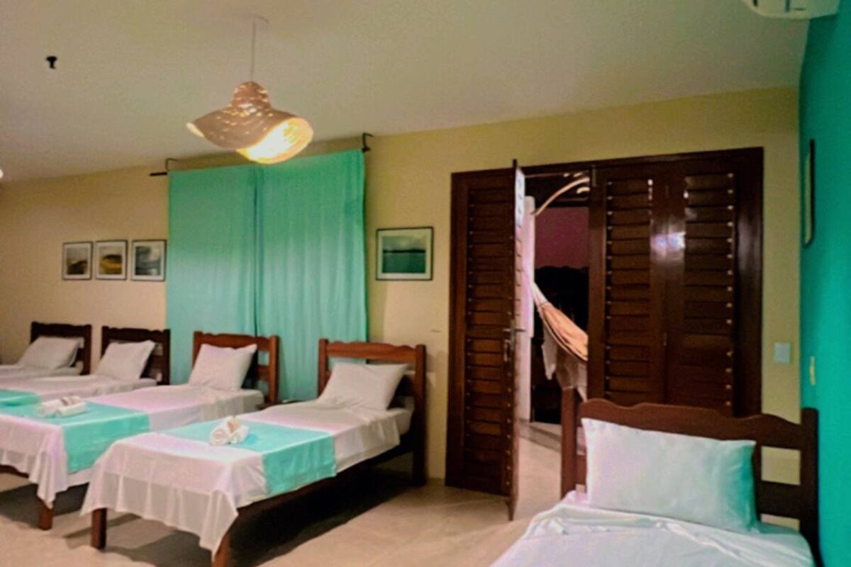 A hotel room with two beds, a ceiling fan, and a door leading to a balcony.