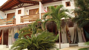 A building with a thatched roof, wooden balconies, and surfboards displayed outside. - Hotel Pousada 360° (Paracuru)