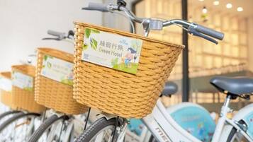 Una fila di biciclette con cestini in vimini, ognuna con un'etichetta che riporta 'Green Hotel'.