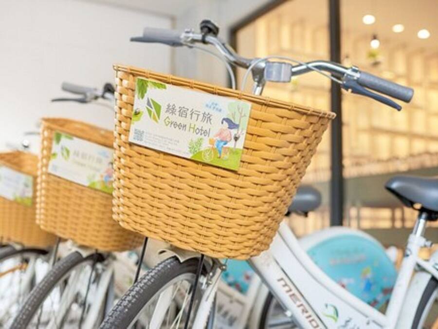 Una fila di biciclette con cestini in vimini, ognuna con un'etichetta che riporta 'Green Hotel'.