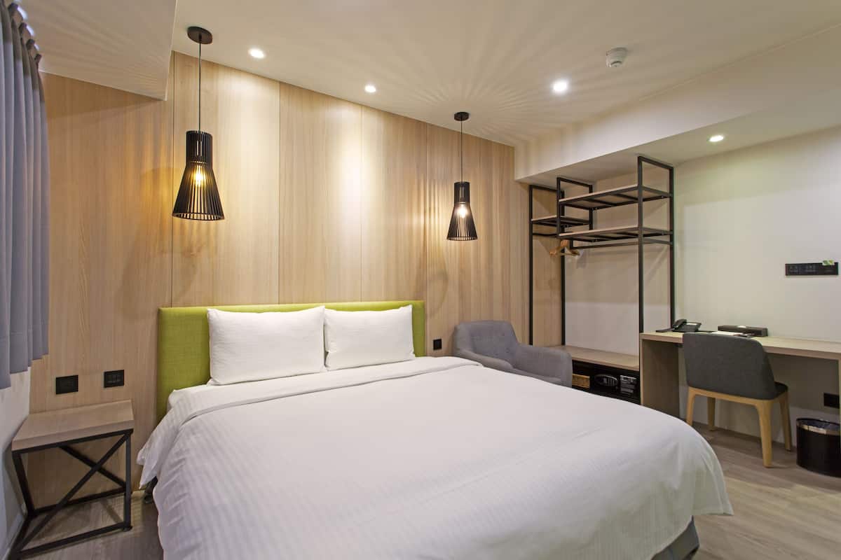Une chambre d’hôtel moderne, dotée d’un grand lit, d’un bureau et d’une chaise.