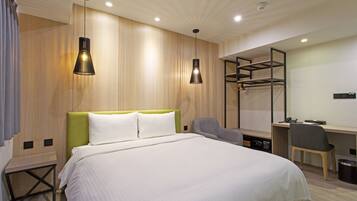 A modern hotel room with a large bed, a desk, and a chair.