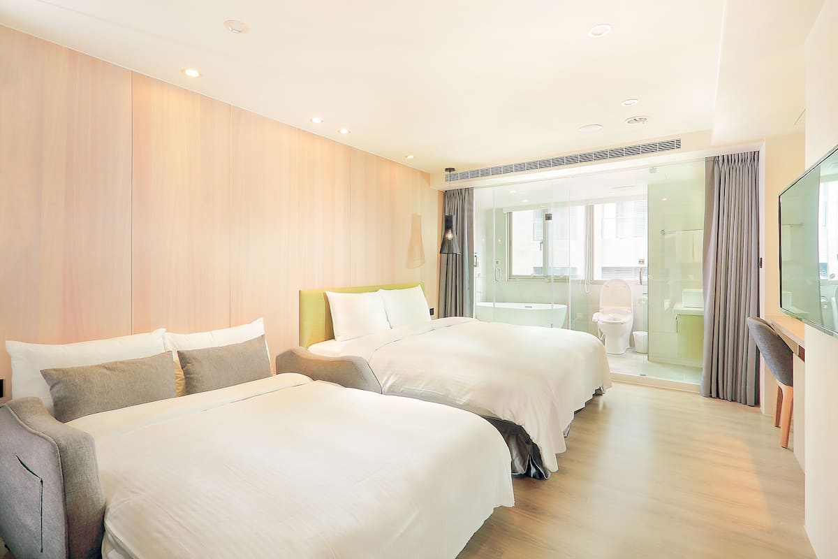 Une chambre d’hôtel avec deux lits, une télévision et un balcon offrant une vue.