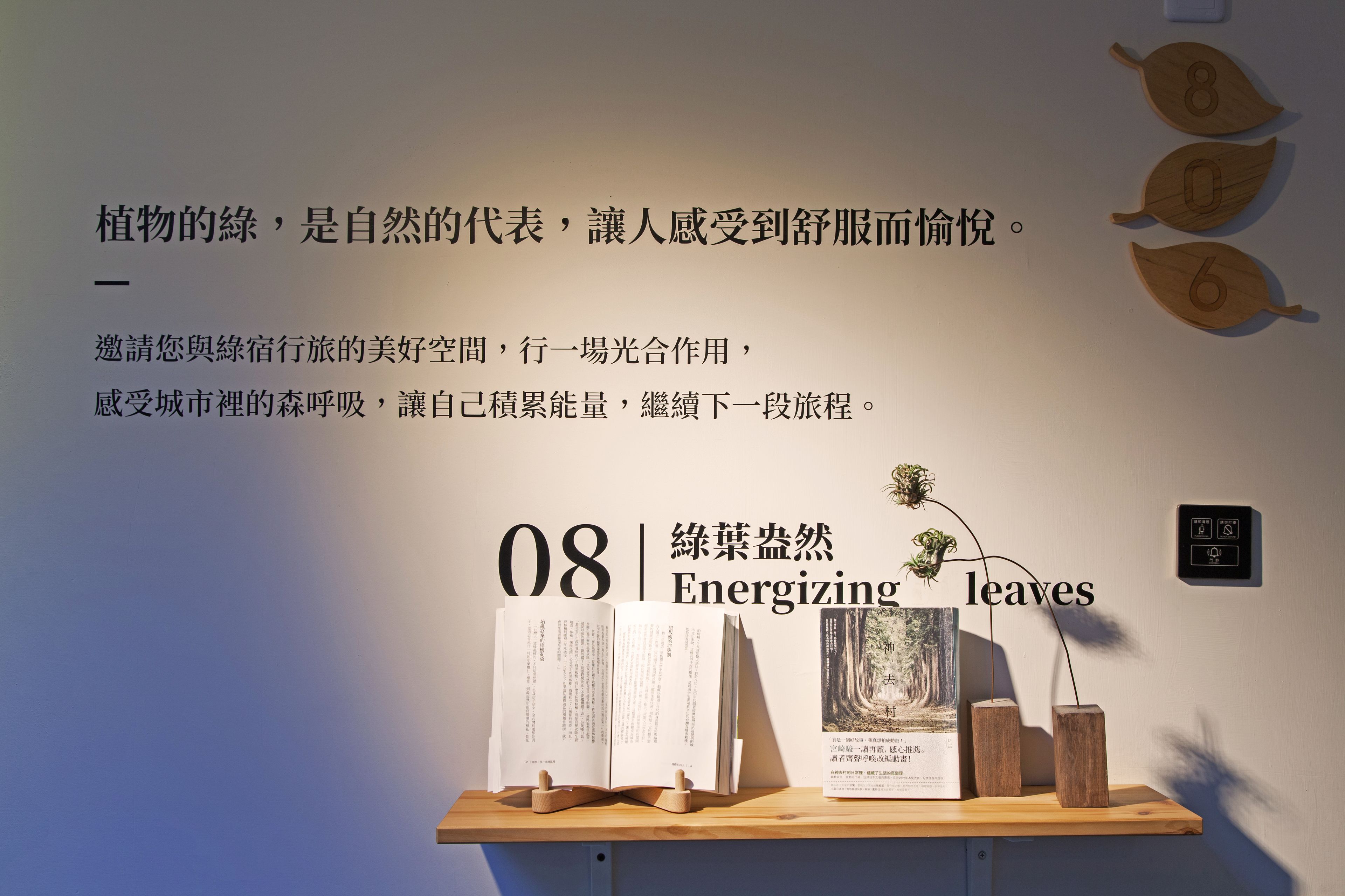 A wall with a text about plants and a wooden shelf with books and a small plant.