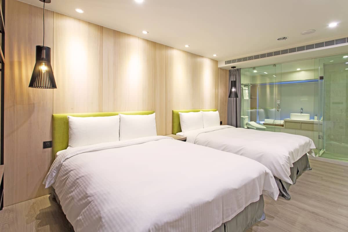 Une chambre d’hôtel avec deux lits, une douche en verre et un design moderne.