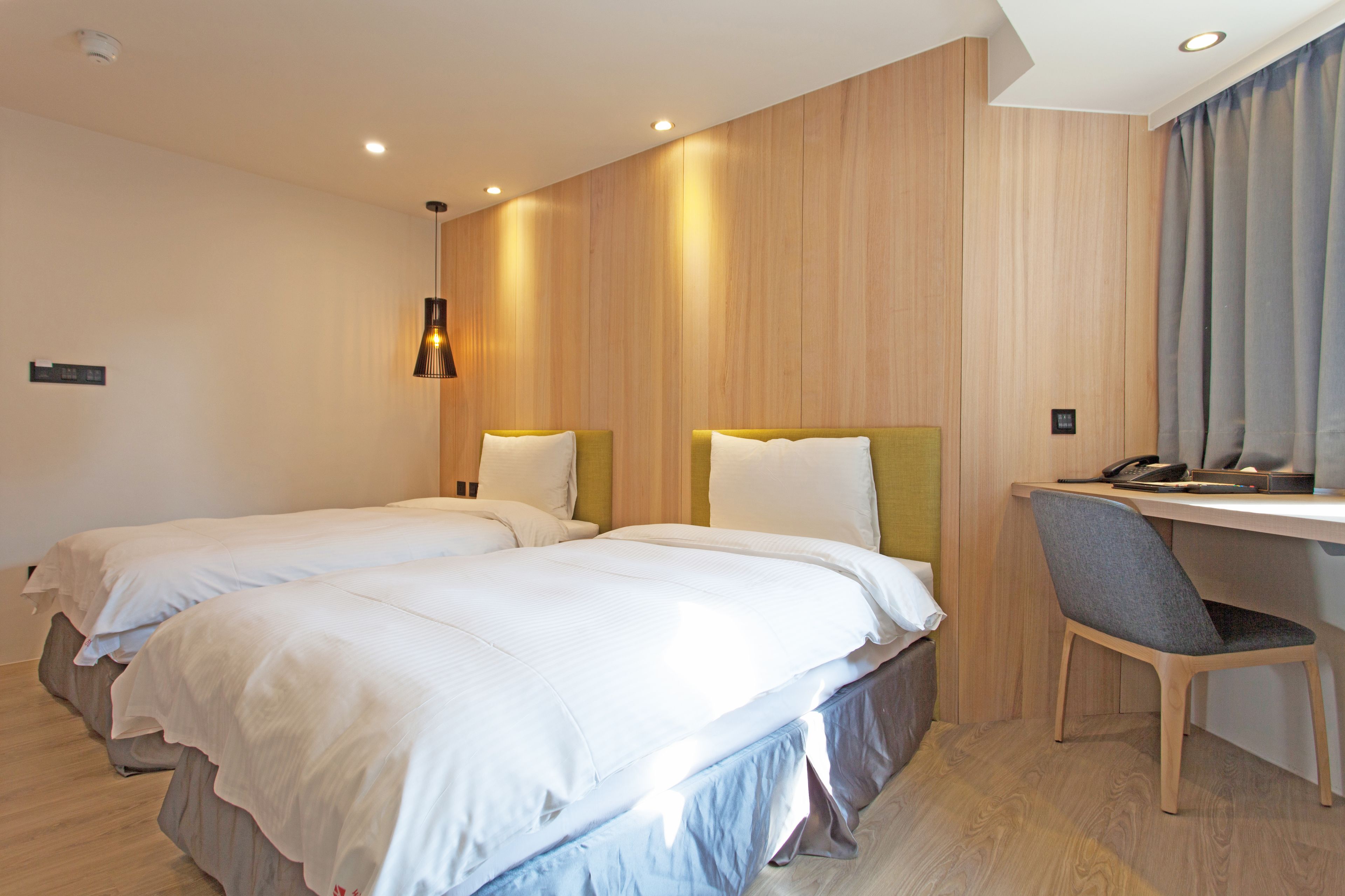 A hotel room with two beds, a desk, and a chair.
